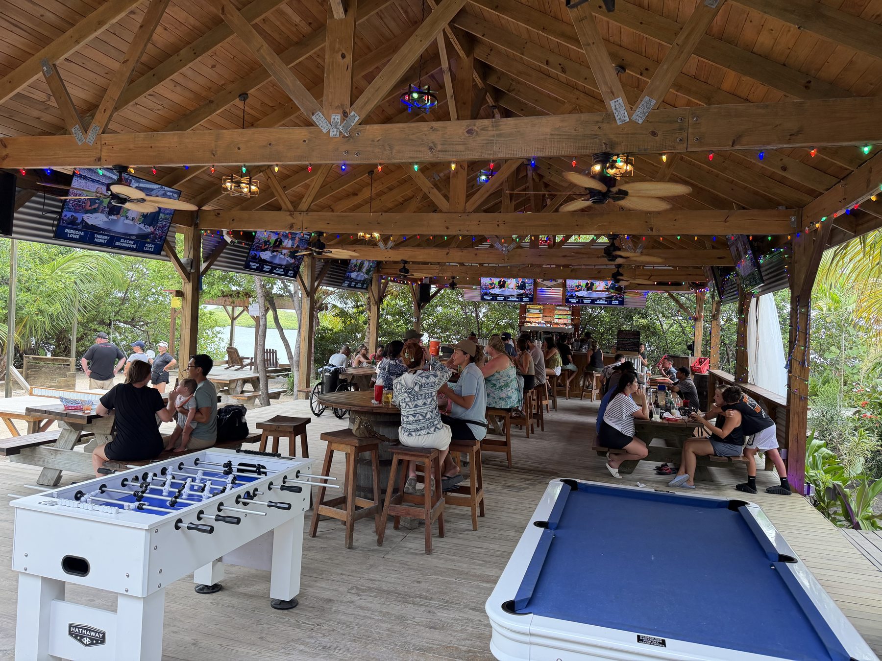 The beer garden by day &mdash; foosball, pool table, screens and the lagoon beyond
